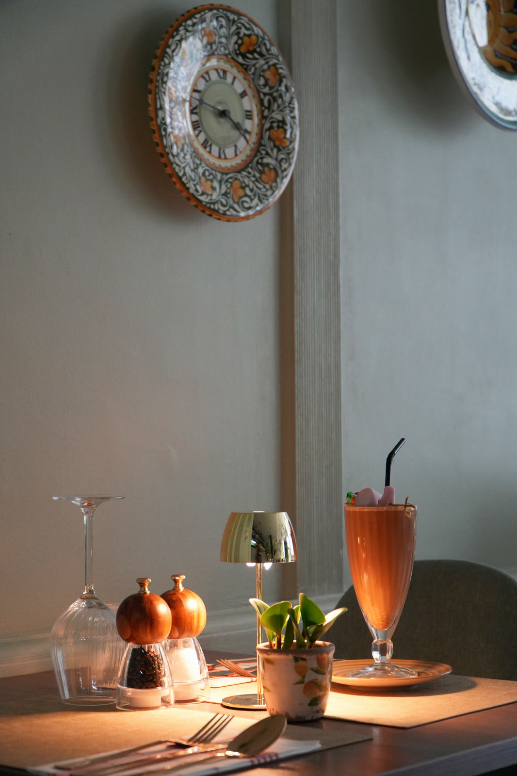 Table set in warm light at A Tavola restaurant, with an Italian ceramic clock
