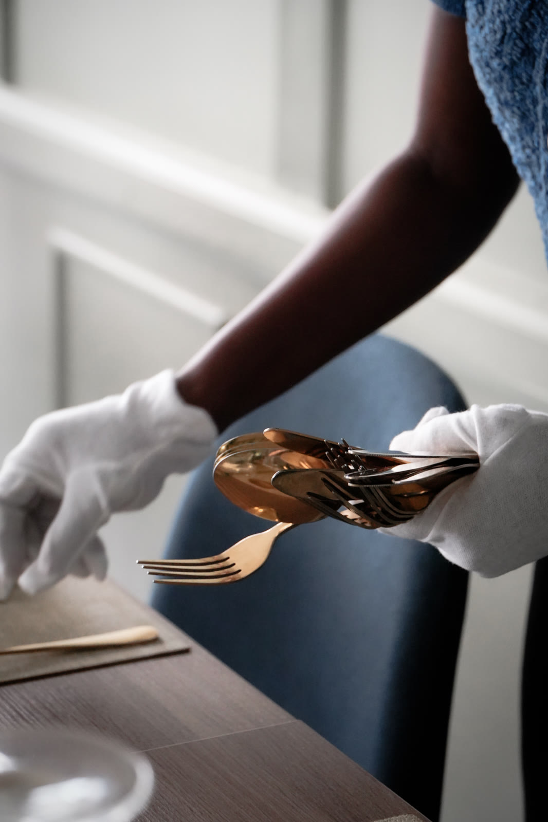 Gloved hands holding gold cutlery at A Tavola